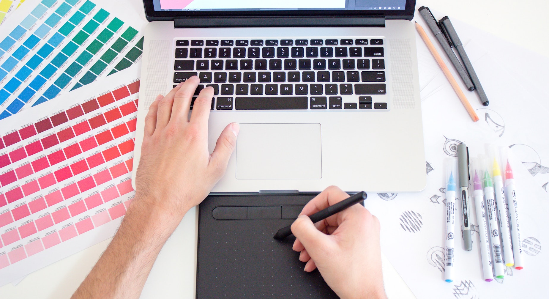 A person works on their laptop next to two swatches of blue and red gradients
